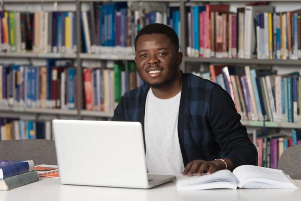 Szczęśliwy Afryki studentowi z laptopa w bibliotece — Zdjęcie stockowe