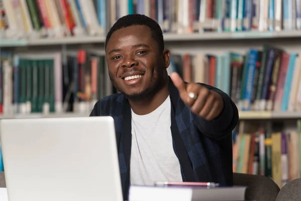 Estudiante africano en una biblioteca mostrando pulgares hacia arriba — Foto de Stock