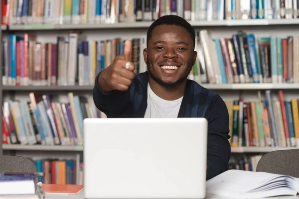 Afrikanska mannen i ett bibliotek visar tummen — Stockfoto