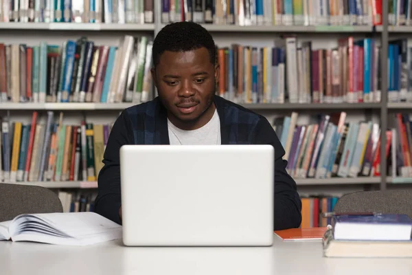 Heureux étudiant africain masculin avec ordinateur portable dans la bibliothèque — Photo