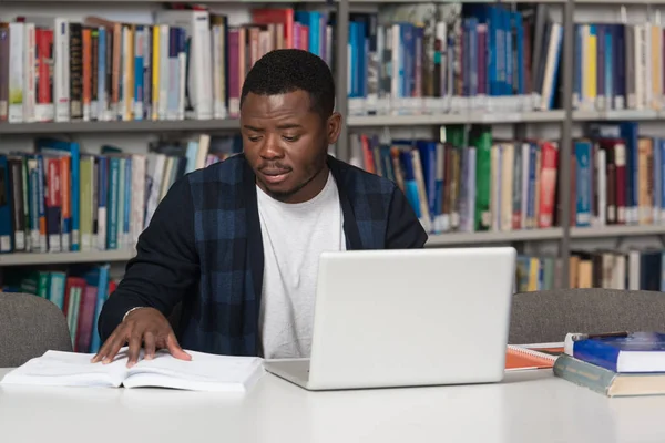 Estudiante africano feliz con el ordenador portátil en la biblioteca — Foto de Stock