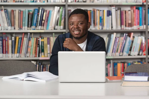 Ung Student med sin Laptop i ett bibliotek — Stockfoto