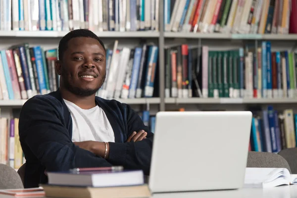 Heureux étudiant africain masculin avec ordinateur portable dans la bibliothèque — Photo