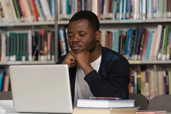 Estudante masculino confuso lendo muitos livros para exame — Fotografia de Stock