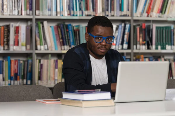 Heureux étudiant africain masculin avec ordinateur portable dans la bibliothèque — Photo