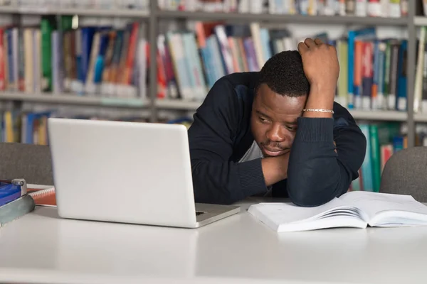 Estudante masculino dormindo na biblioteca — Fotografia de Stock