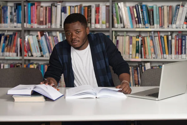 Jovem estudante usando seu laptop em uma biblioteca — Fotografia de Stock