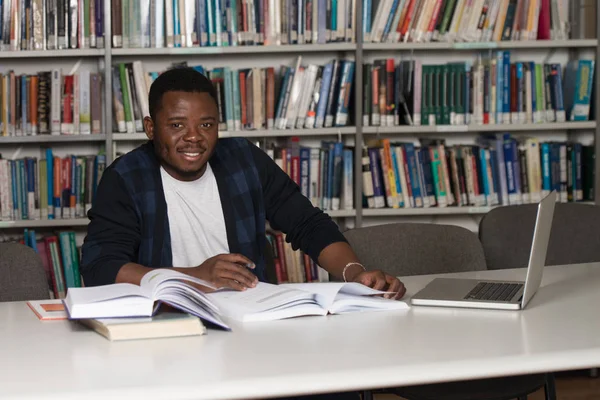 Mladý Student pomocí jeho notebook v knihovně — Stock fotografie