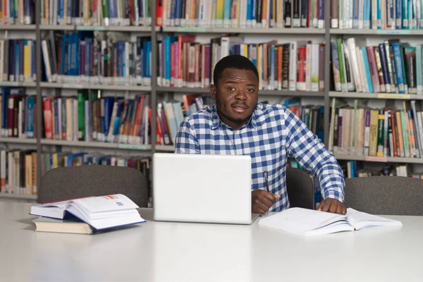 Heureux étudiant africain masculin avec ordinateur portable dans la bibliothèque — Photo