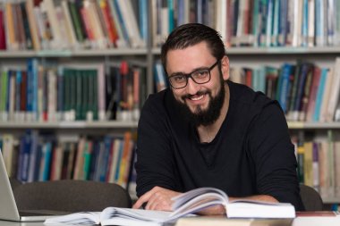 Diz üstü bir kütüphaneyi kullanan genç öğrenci