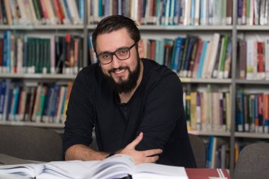 Diz üstü bir kütüphaneyi kullanan genç öğrenci