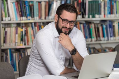 Kütüphane içinde Laptop ile mutlu erkek öğrenci