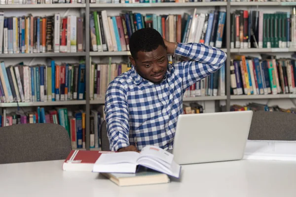 Estudante masculino confuso lendo muitos livros para exame — Fotografia de Stock