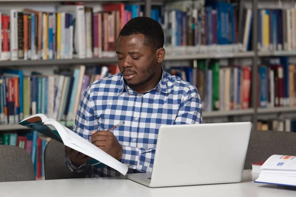 Heureux étudiant africain masculin avec ordinateur portable dans la bibliothèque — Photo