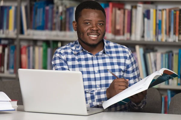 Heureux étudiant africain masculin avec ordinateur portable dans la bibliothèque — Photo