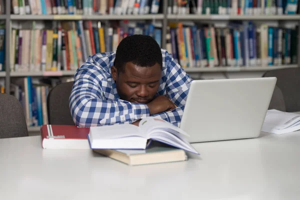 Estudante masculino dormindo na biblioteca — Fotografia de Stock