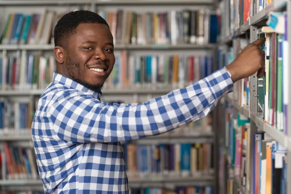 Beau jeune étudiant dans une bibliothèque — Photo