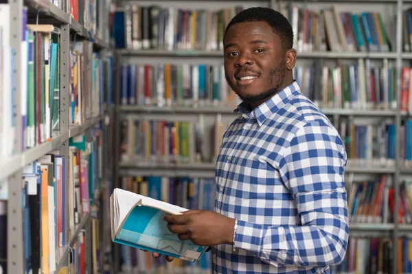 Bello giovane studente universitario in una biblioteca — Foto Stock