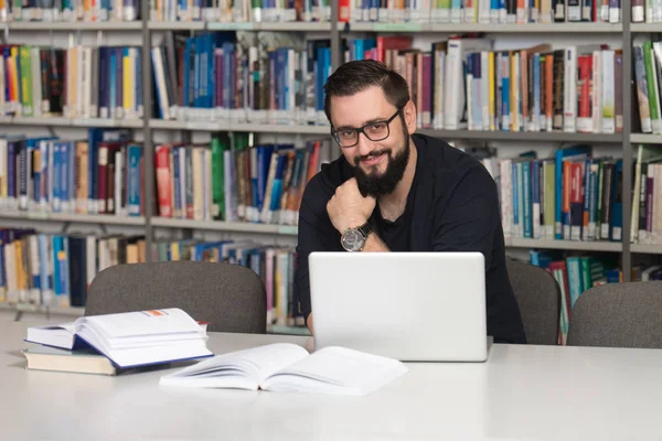 Estudiante joven usando su computadora portátil en una biblioteca —  Fotos de Stock