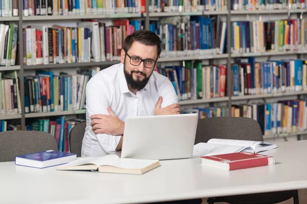 Feliz estudiante masculino con ordenador portátil en la biblioteca —  Fotos de Stock