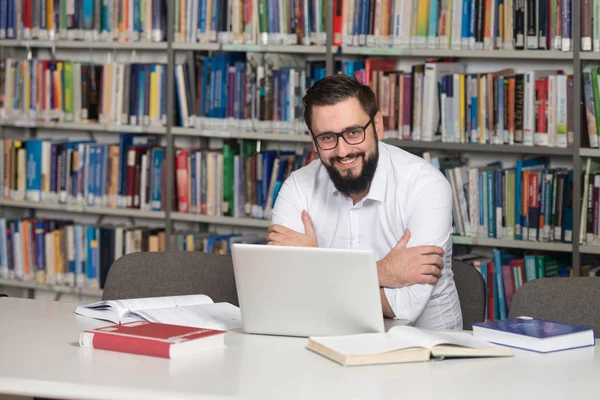 Jovem estudante usando seu laptop em uma biblioteca — Fotografia de Stock