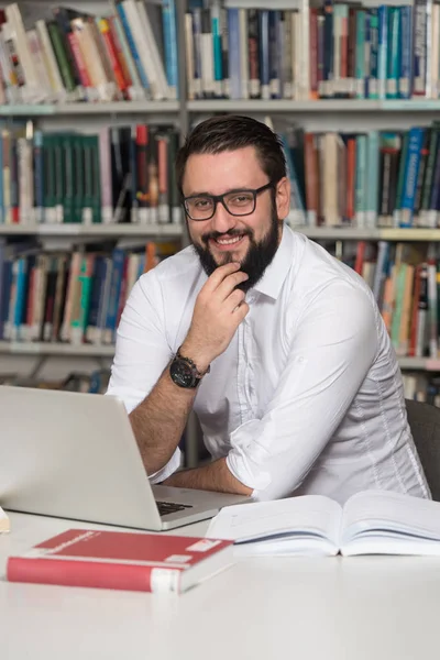 Jovem estudante usando seu laptop em uma biblioteca — Fotografia de Stock