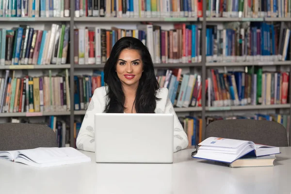 Estudiante joven usando su computadora portátil en una biblioteca —  Fotos de Stock