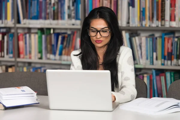 Jeune étudiante utilisant son ordinateur portable dans une bibliothèque — Photo