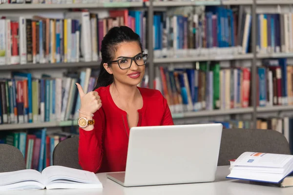 Estudiante feliz trabajando con el ordenador portátil en la biblioteca —  Fotos de Stock