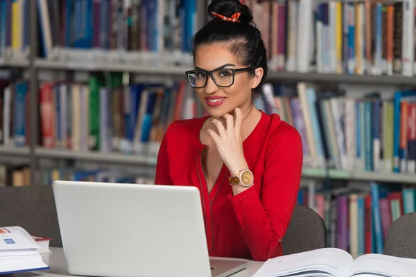 Étudiante heureuse travaillant avec un ordinateur portable dans la bibliothèque — Photo