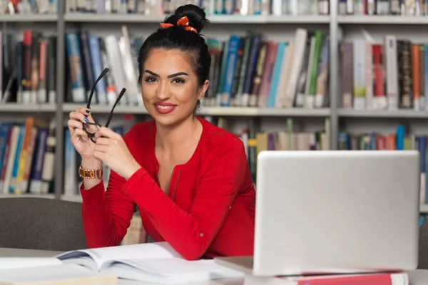 Estudiante joven usando su computadora portátil en una biblioteca — Foto de Stock