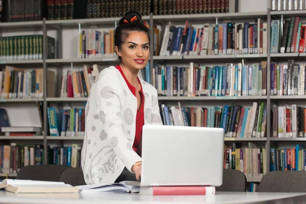 Étudiante heureuse travaillant avec un ordinateur portable dans la bibliothèque — Photo