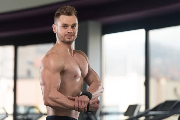 Musculoso hombre flexionando los músculos en el gimnasio — Foto de Stock