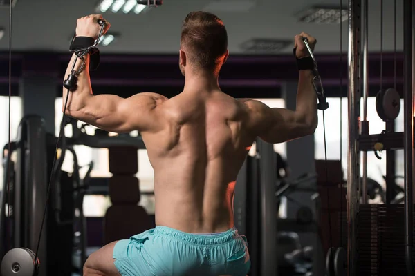 Homem muscular exercitando ombros na máquina — Fotografia de Stock