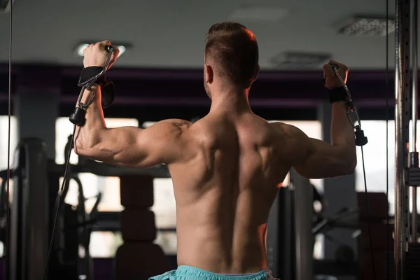 Muskulöser Mann, der Schultern an Maschine trainiert — Stockfoto