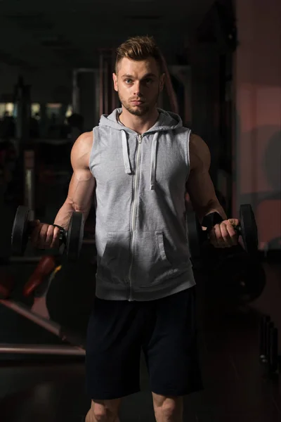 Bodybuilder exerçant des biceps avec des haltères dans le gymnase — Photo