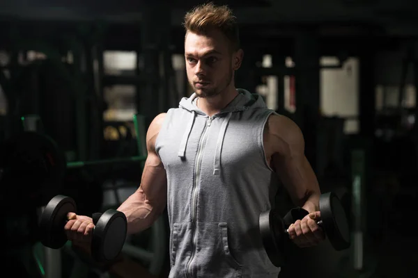 Kulturista cvičení Biceps s činkami v tělocvičně — Stock fotografie