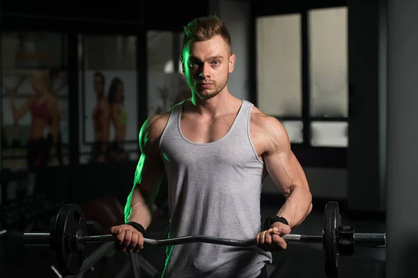 Man in de sportschool uitoefening biceps met barbell — Stockfoto