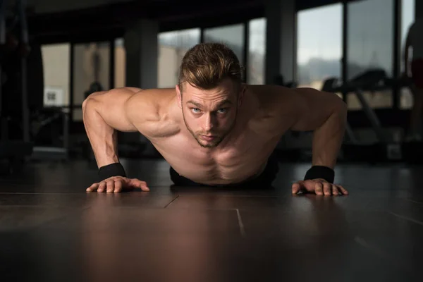 Joven haciendo prensa sube en el gimnasio — Foto de Stock