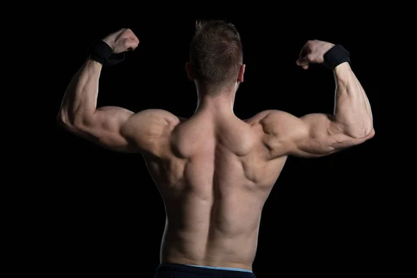Muskulöse Männer, die auf schwarzem Hintergrund die Muskeln spielen lassen — Stockfoto