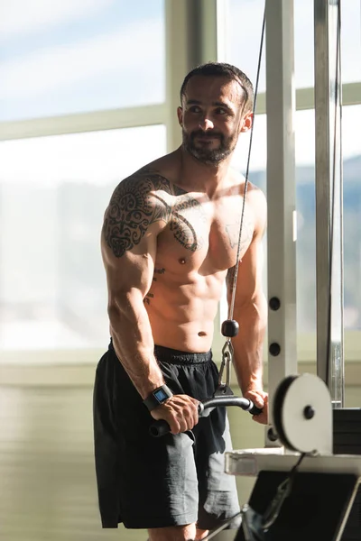 Мускулистый человек, выполняющий упражнения на тренажерах — стоковое фото