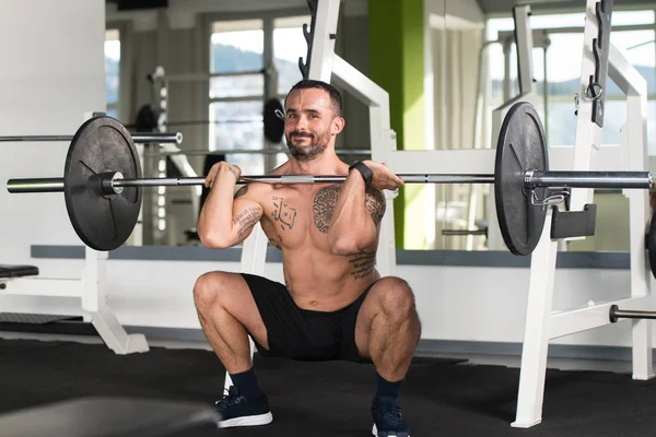 Homem que faz o exercício pesado do peso com barra — Fotografia de Stock