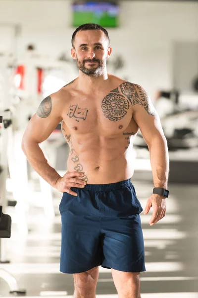 Musculoso hombre flexionando los músculos en el gimnasio —  Fotos de Stock