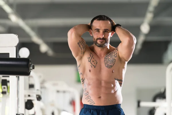 Musculoso hombre flexionando los músculos en el gimnasio —  Fotos de Stock