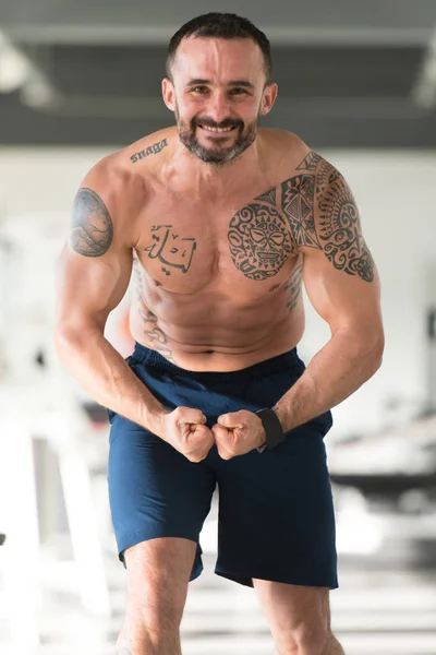 Hombre en el gimnasio mostrando su cuerpo bien entrenado — Foto de Stock