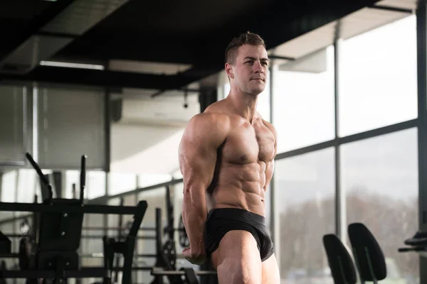 Hombre musculoso guapo flexionando músculos en el gimnasio —  Fotos de Stock