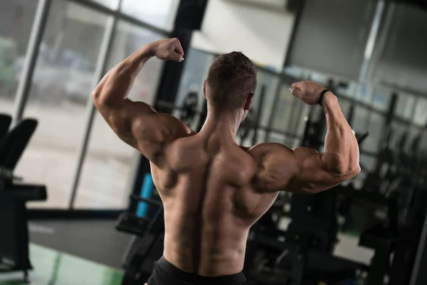 Homem muscular que flexiona a dose dos músculos traseiros — Fotografia de Stock