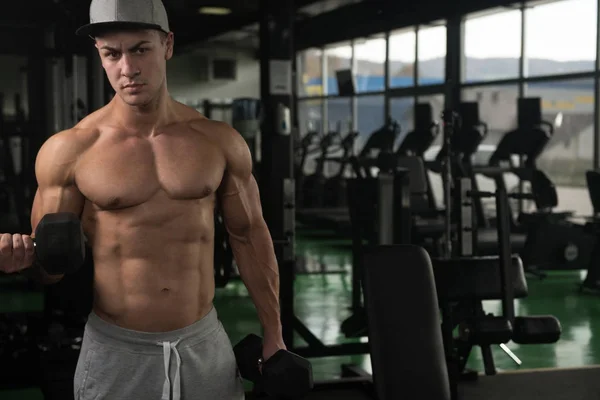 Hombre muscular ejercitando bíceps con mancuerna —  Fotos de Stock