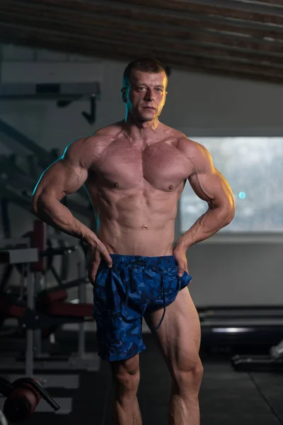 Muž v tělocvičně ukazující jeho dobře vyškolených tělo — Stock fotografie