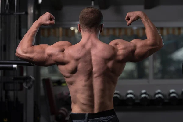 Homem muscular que flexiona a dose dos músculos traseiros — Fotografia de Stock